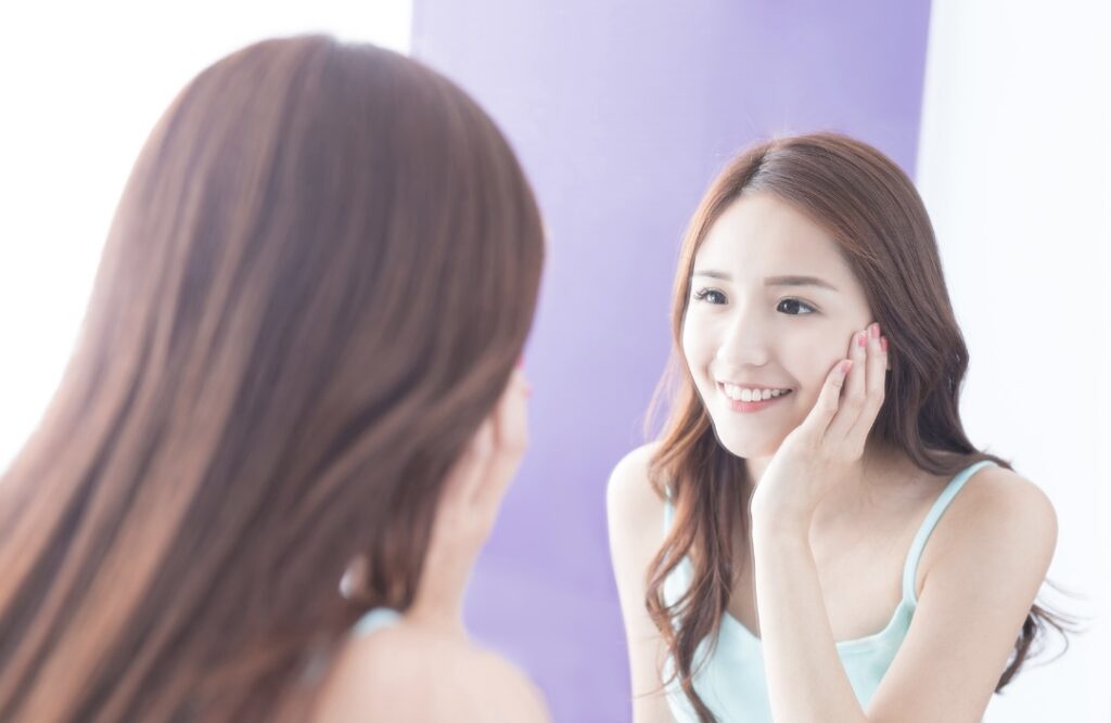 鏡を見て微笑む女性
